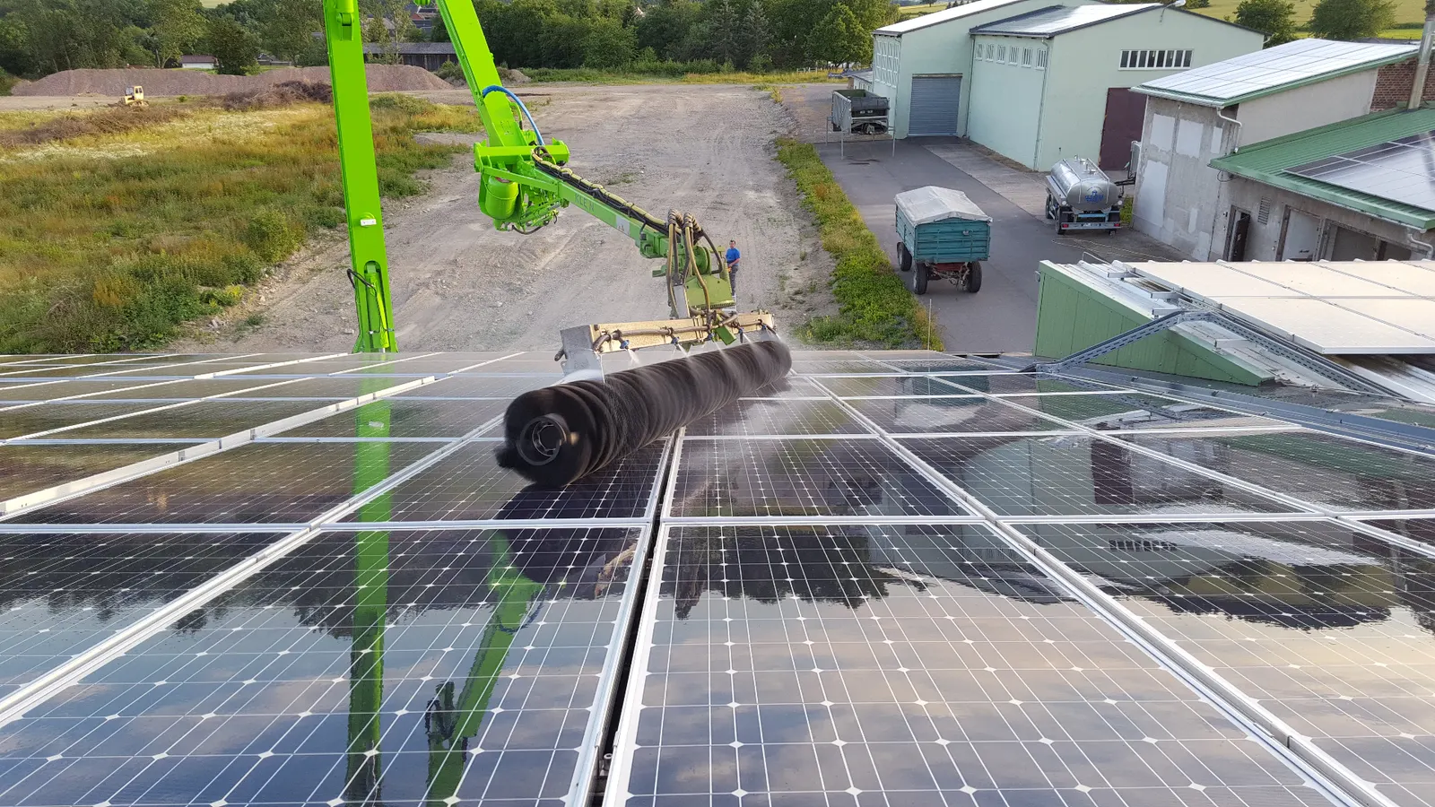 Rotierende Bürste reinigt PV-Module mit Wasser auf einem Hallendach